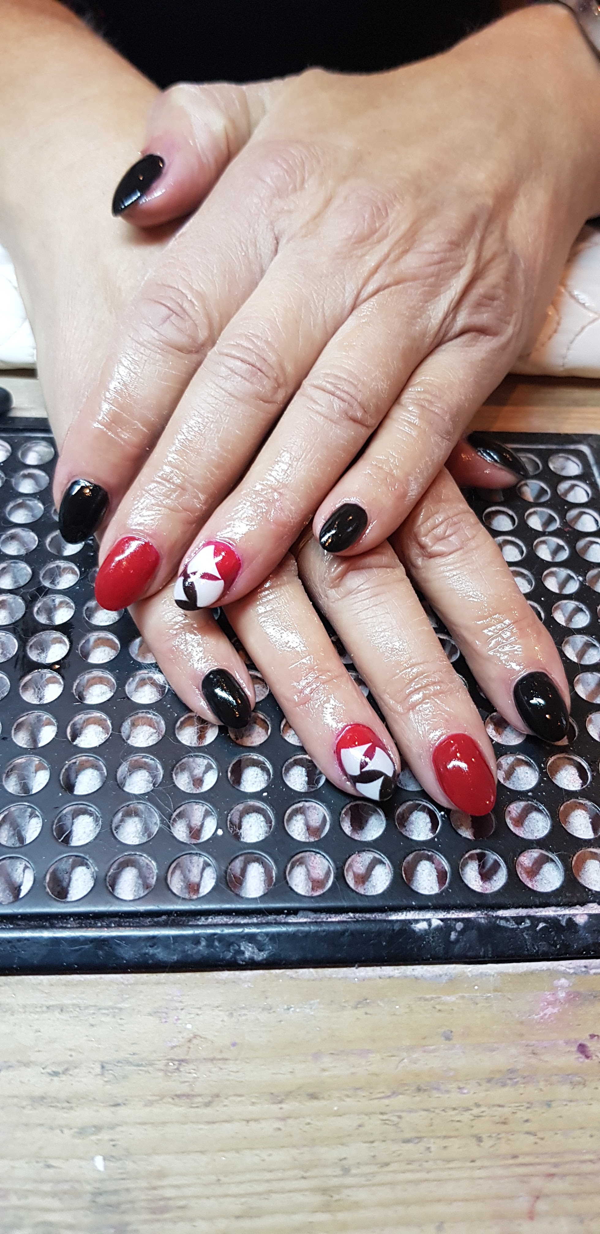 Gelnagels in rood en zwart, met een kleine afbeelding op twee nagels